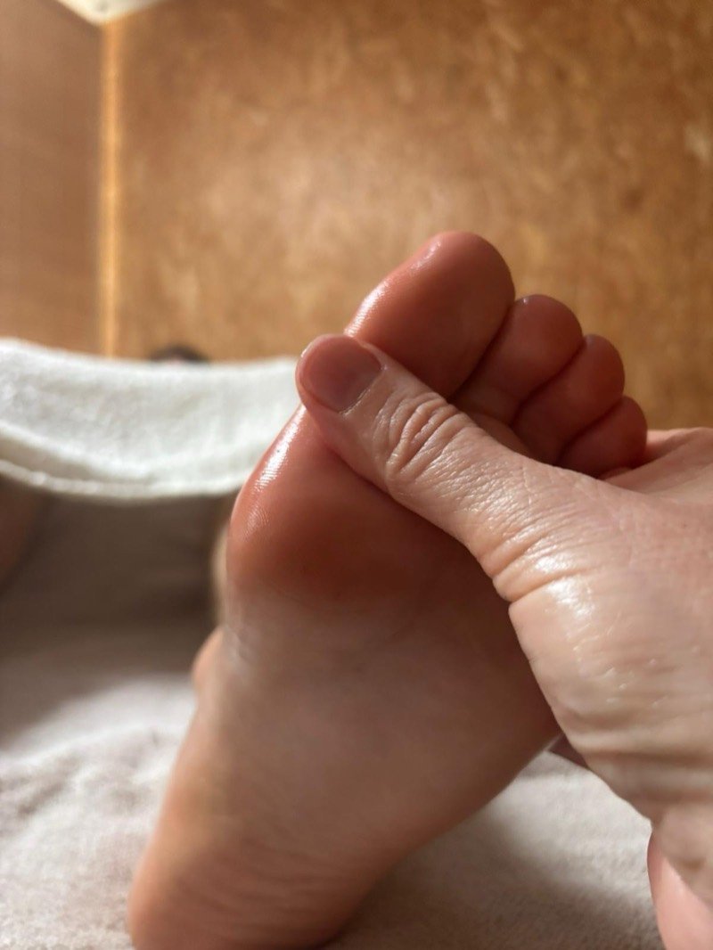 Séance de réflexologie plantaire : pression du pouce sous les orteils